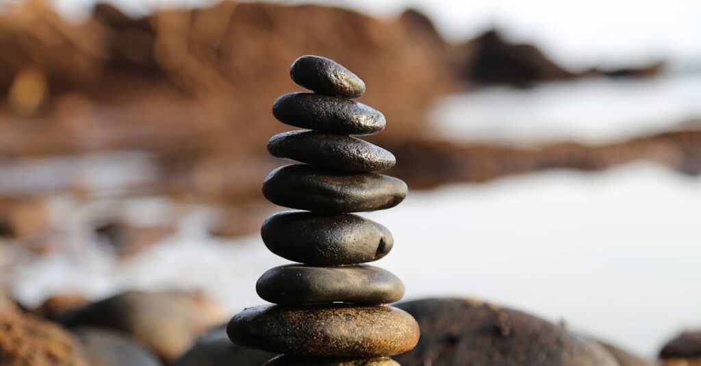 A stack of smooth stones artfully balanced by a waterside, evoking tranquility and zen.