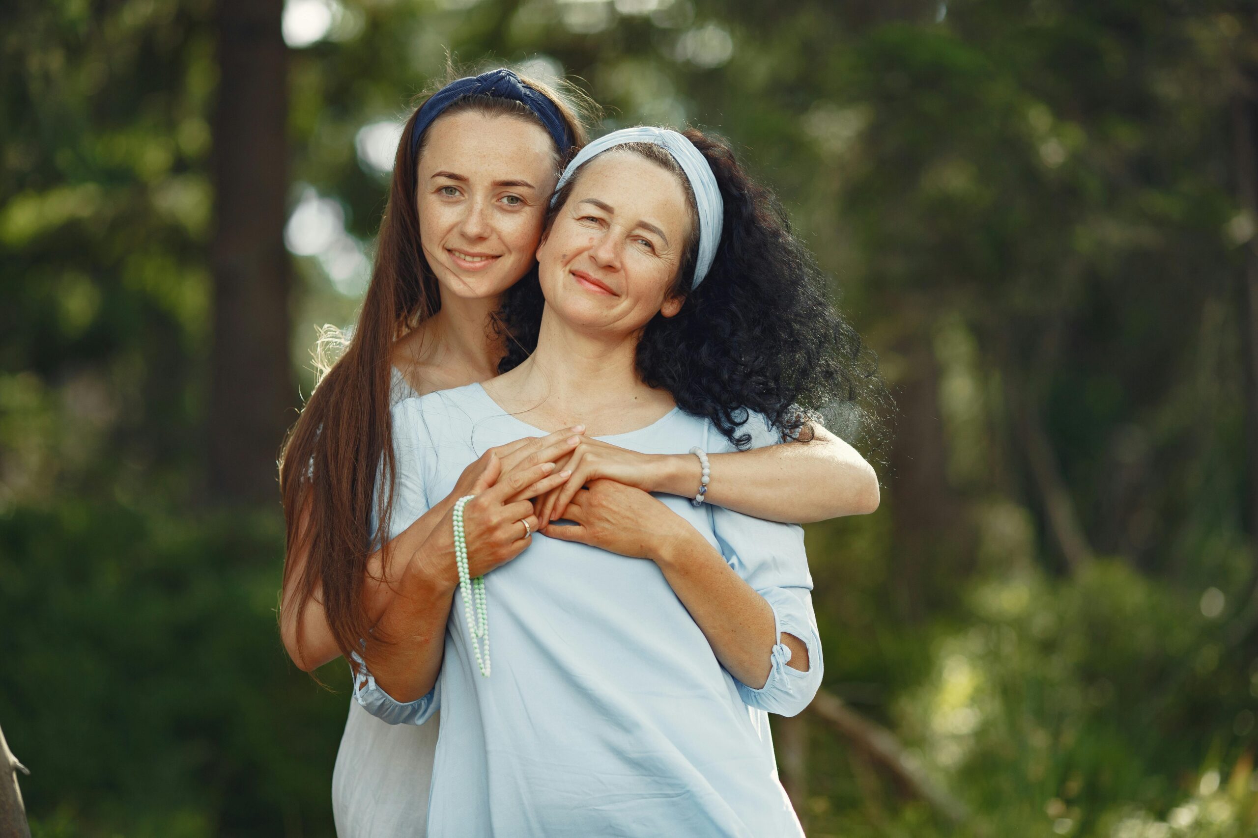 A loving moment between a mother and daughter in a sunny outdoor setting.